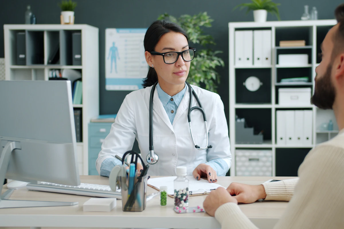 Ärztin bespricht Unterlagen mit einem Patienten am Schreibtisch